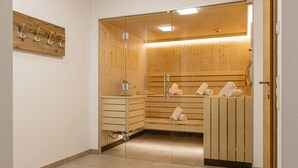 En bastu med träbänkar och en glasvägg. Det finns handdukar på bänkarna och en träbänk med en handduk på.