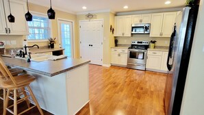 A kitchen with wooden flooring, white cabinets, a stainless steel oven, and a refrigerator. - Spacious 5-bedroom lakefront house in Anderson, 13 miles to Clemson (Anderson)