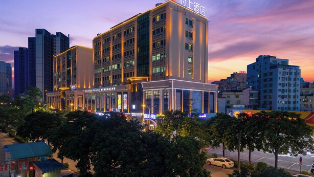 A multi-story hotel with a prominent sign, surrounded by other buildings and trees. - FuShang Hotel (Foshan)