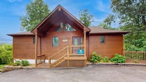 A wooden lodge with a steep gabled roof, a front porch with a staircase, and a sign that reads "The Lodge." - Expansive home with arcade game, pool table, & Great Smoky Mountains view (Gatlinburg)