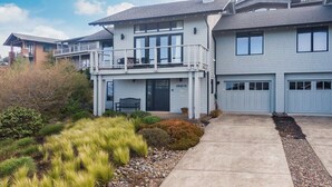 Ein zweistöckiges Haus mit Balkon, Garage und Veranda.