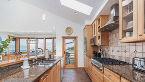 Eine moderne Küche mit Granit Arbeitsplatten, Holzschränken und Blick durch die Tür.