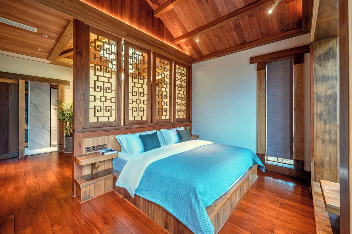 A spacious bedroom with a large bed, wooden headboard, and a view of the outdoors.