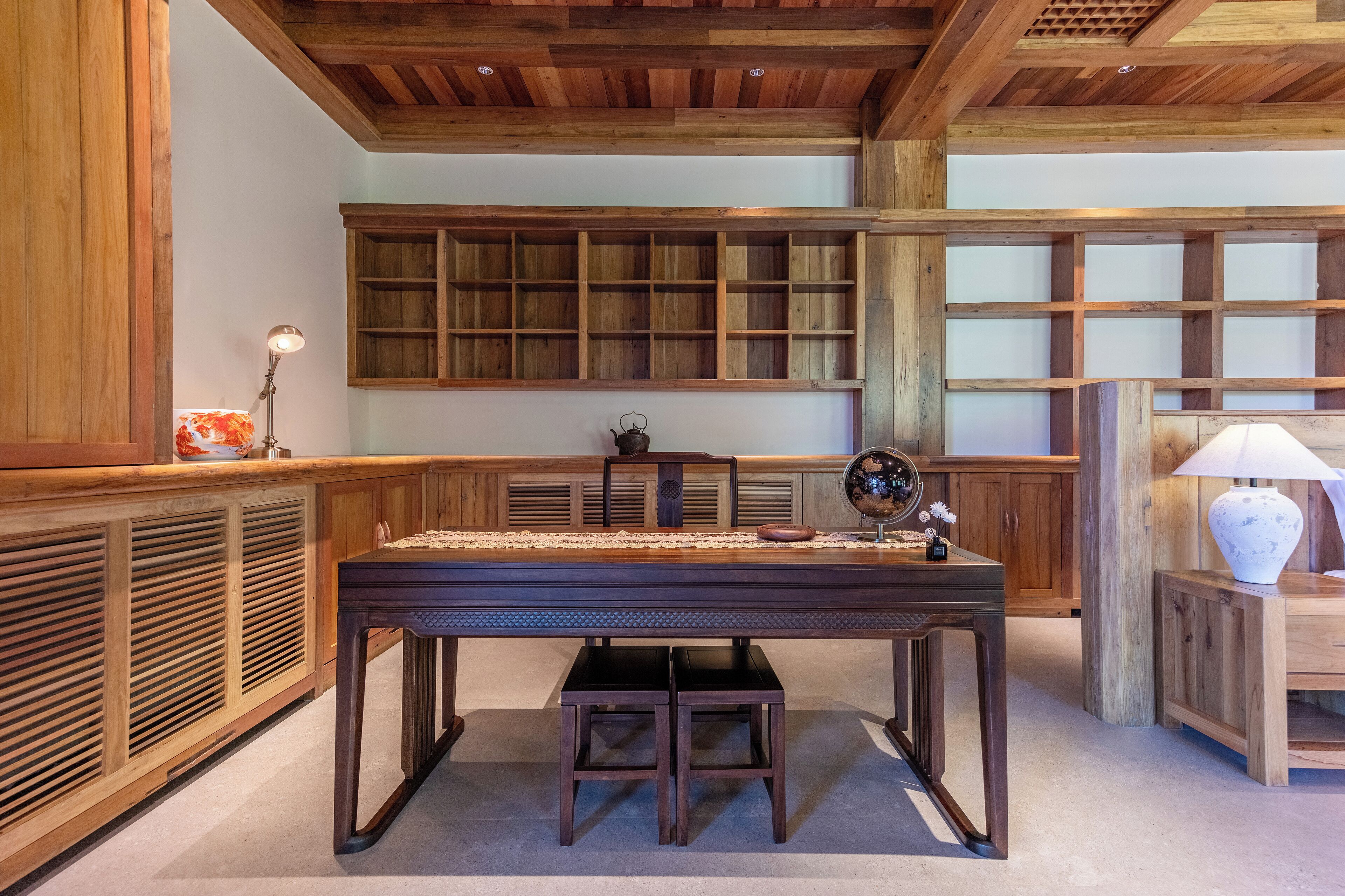 A wooden interior with a central table, benches, and built-in shelving.