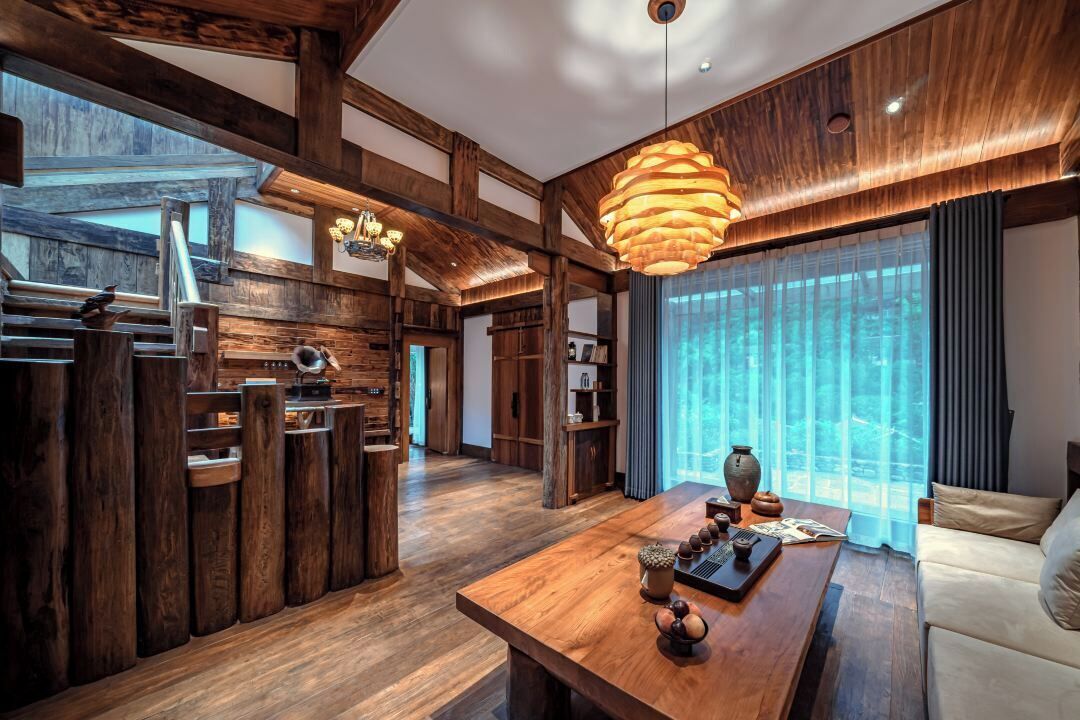 A spacious room with a wooden floor, a large wooden dining table, and a modern pendant light.