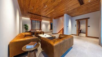 A modern living room with leather sofas, a coffee table, and a staircase leading to another level.