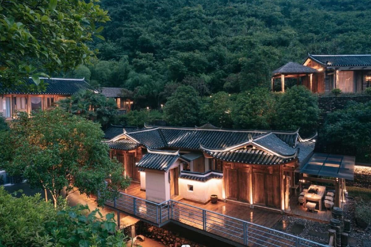 A traditional-style building with a wooden exterior and tiled roof, surrounded by lush greenery and a small waterfall.