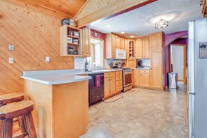 Una cocina con armarios de madera, una isla central y un refrigerador de acero inoxidable.