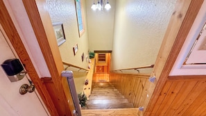 A wooden staircase with a handrail, leading to a door with a small window.