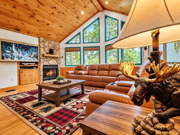 Una sala acogedora con chimenea, sofá de cuero y un ventanal grande.