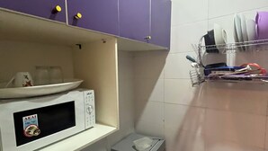 A kitchen with purple cabinets, a microwave, a small refrigerator, and a dish rack with utensils. - Private, Cozy, CityCentre Studio Apartment in the heart of Abuja (Abuja)