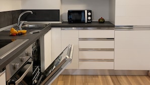 Eine moderne Küche mit weißen Schränken, einer schwarzen Mikrowelle und einem Edelstahlbackofen.