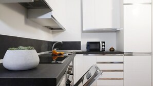 Eine moderne Küche mit weißen Schränken, einer schwarzen Arbeitsplatte, einem eingebauten Backofen, einer Mikrowelle und einem kleinen Topfpflanzen.