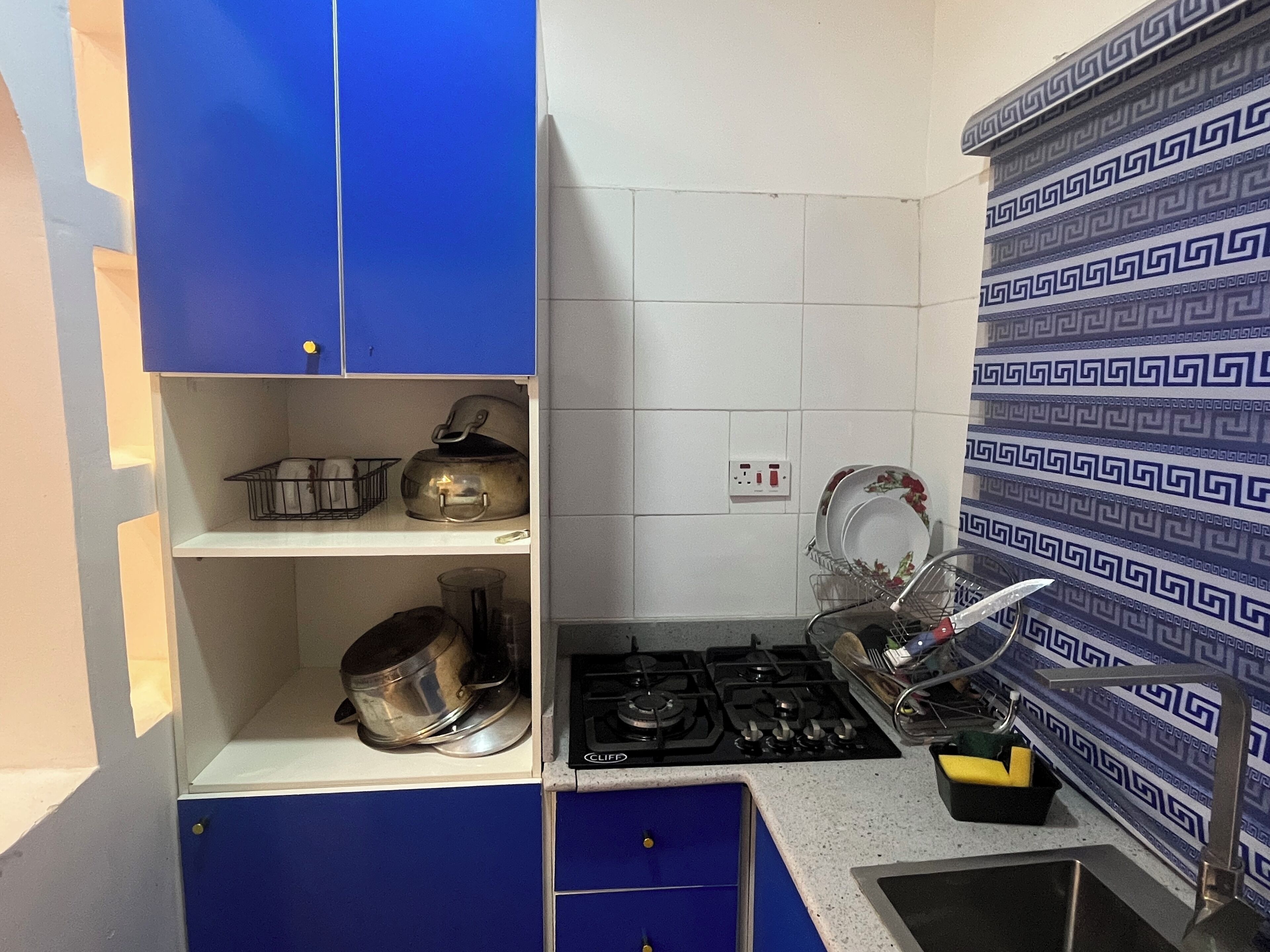 A compact kitchen with blue cabinets, a gas stove, and a sink.