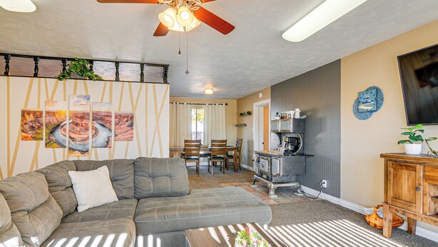 Sala de estar con sofá modular, ventilador de techo y comedor con mesa y sillas.