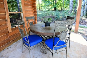 Une cabane en bois avec une table ronde et quatre chaises dotées de coussins bleus.