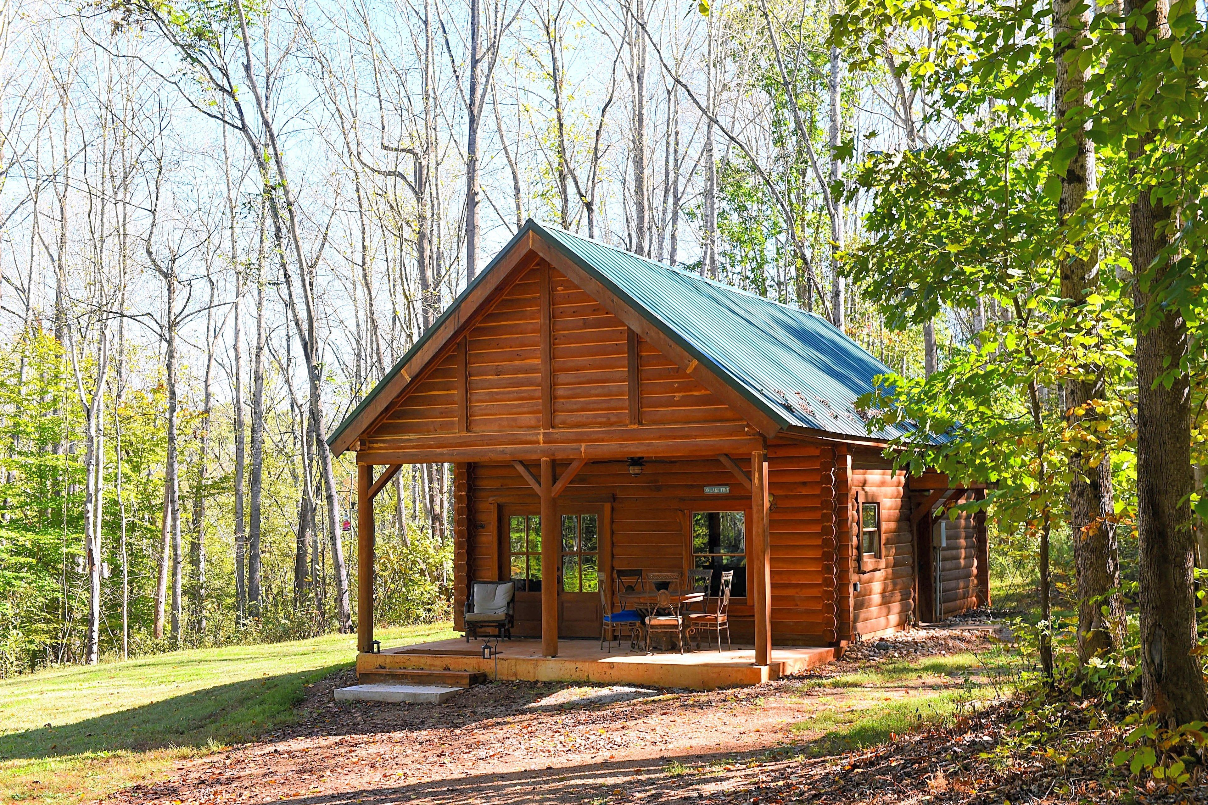 A wooden cabin with a covered porch, a dining area, and a fireplace.