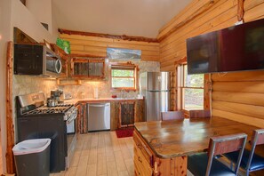 A compact kitchen with wooden walls, a stove, a refrigerator, and a microwave. - Secluded Cabin w/ Dock Access in Pittsville (Pittsville)