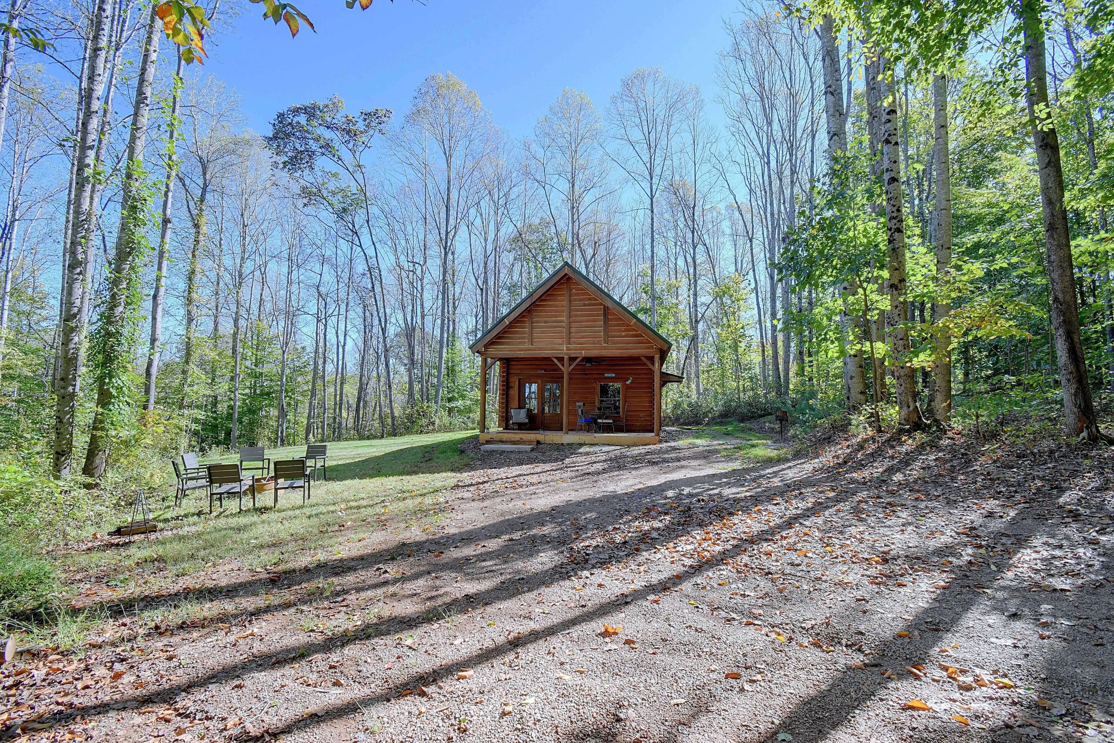 A cabin with a porch and seating area, surrounded by a forest.