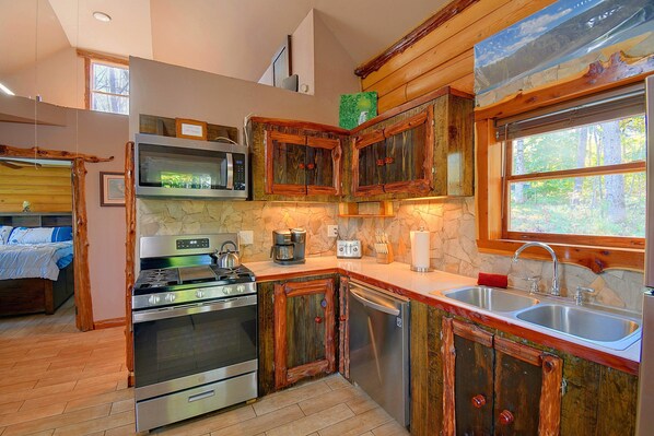 A kitchen with wooden cabinets, a stove, microwave, and a sink.