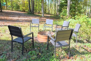 A group of metal chairs arranged in a circle around a fire pit in a forested area. - Secluded Cabin w/ Dock Access in Pittsville (Pittsville)