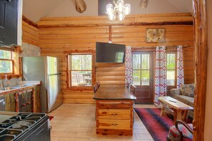 A cabin interior with a kitchen, dining area, and a fireplace. - Secluded Cabin w/ Dock Access in Pittsville (Pittsville)