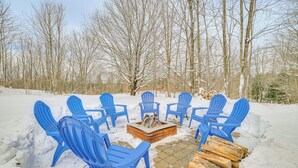 A snow-covered outdoor seating area with blue chairs arranged around a central fire pit. - 22 Mi to Boyne Mountain: Home w/ Fire Pit! (Petoskey)