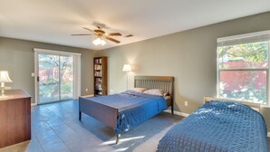 Een slaapkamer met een bed, een bureau, een boekenkast en een raam.
