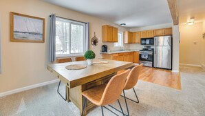 Eine geräumige Küche mit Holzschränken, einem Edelstahlkühlschrank und einem Essbereich mit großem Tisch und Stühlen.
