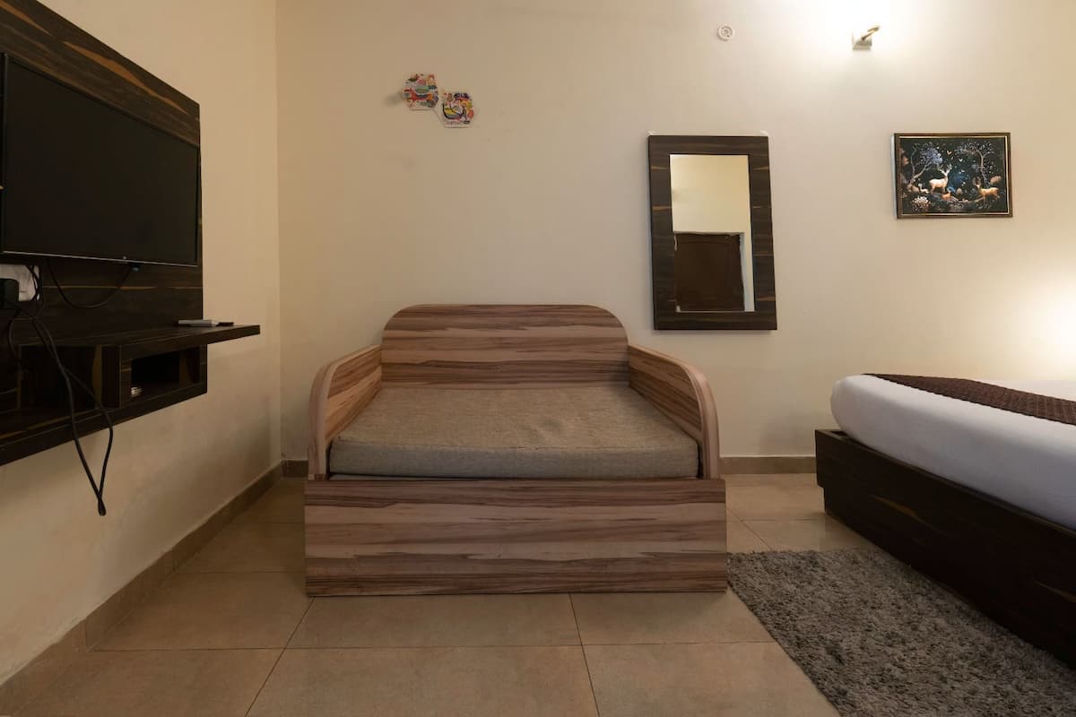 A bedroom with a built-in bench, a TV mounted on the wall, a mirror, and a framed picture.