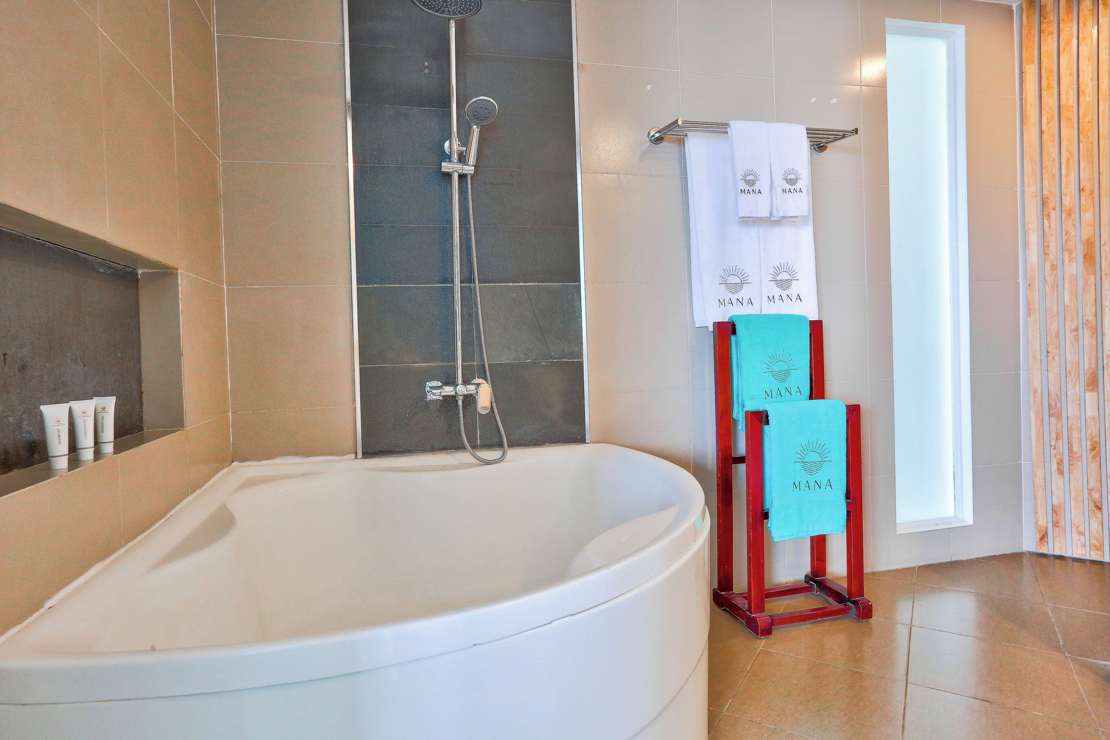 A modern bathroom with a large bathtub, a showerhead, and a towel rack with towels.