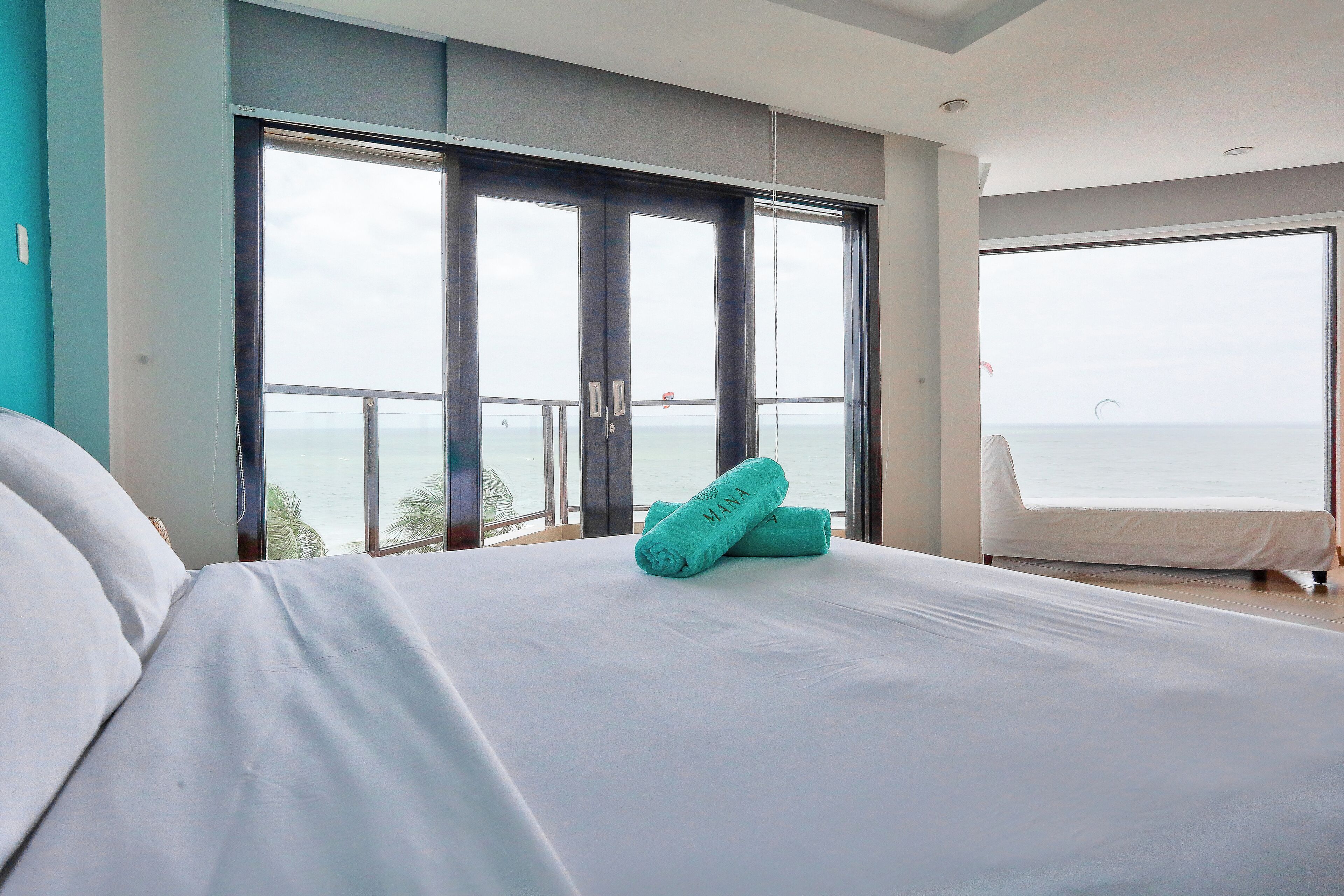 Une chambre d’hôtel avec un grand lit, un balcon donnant sur la mer et une porte coulissante.