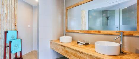 Un baño moderno con tocador de madera, dos lavamanos y un espejo grande.