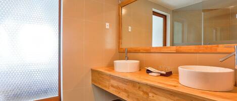 Une salle de bain moderne avec deux lavabos, un grand miroir et une porte en verre dépoli.