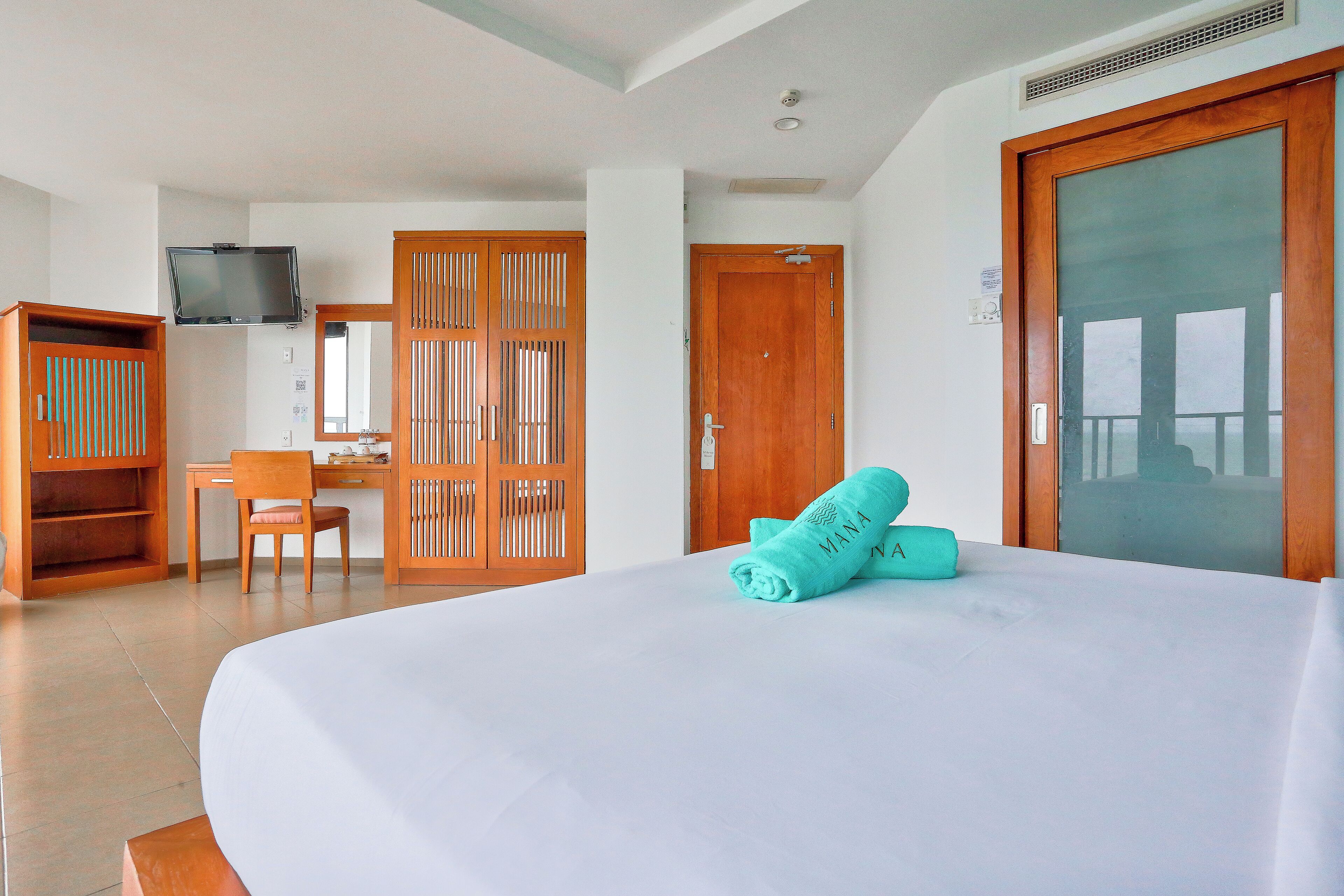A hotel room with a bed, a desk, a chair, a television, and a wardrobe.