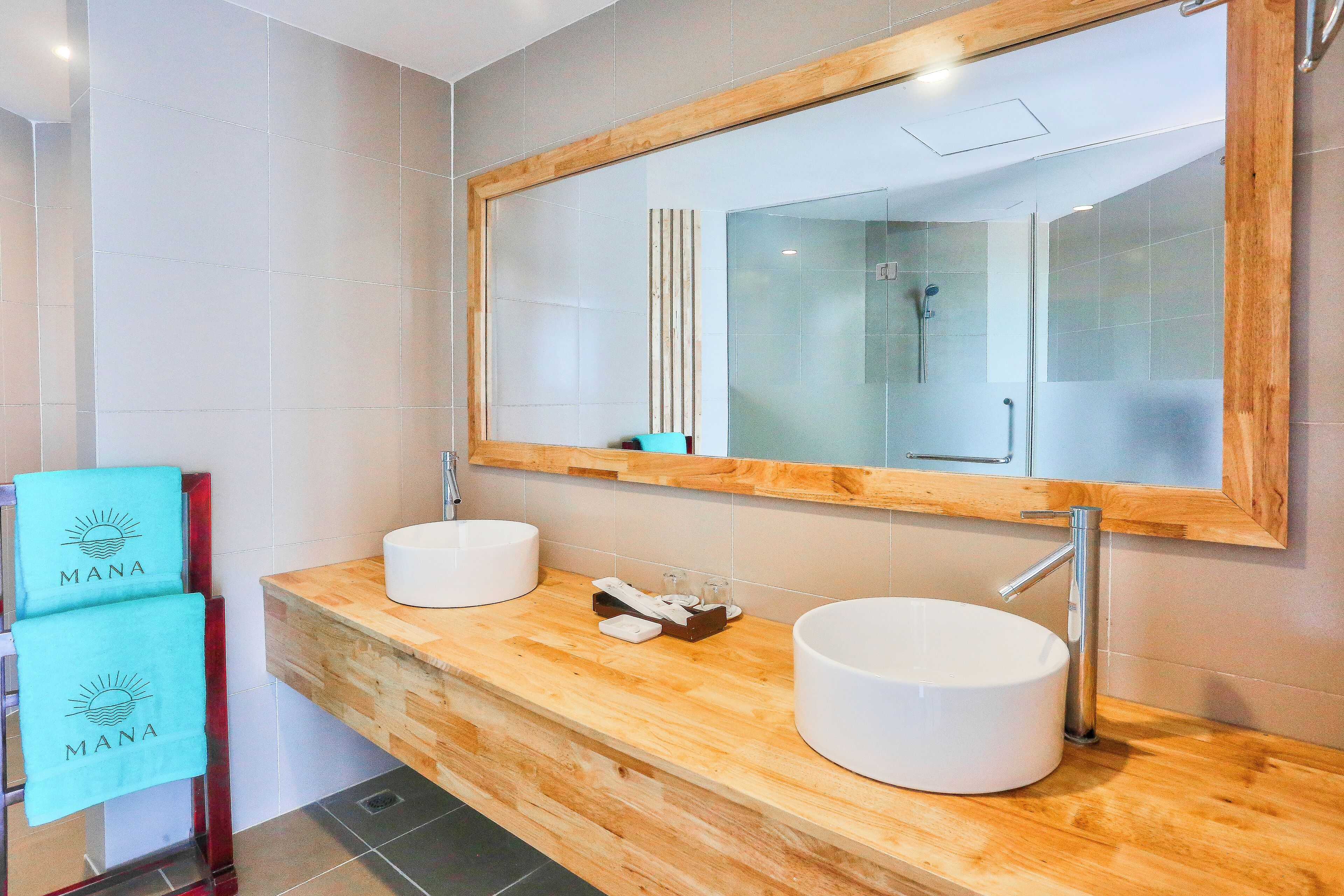 Un baño moderno con dos lavamanos, un espejo grande y encimeras de madera.