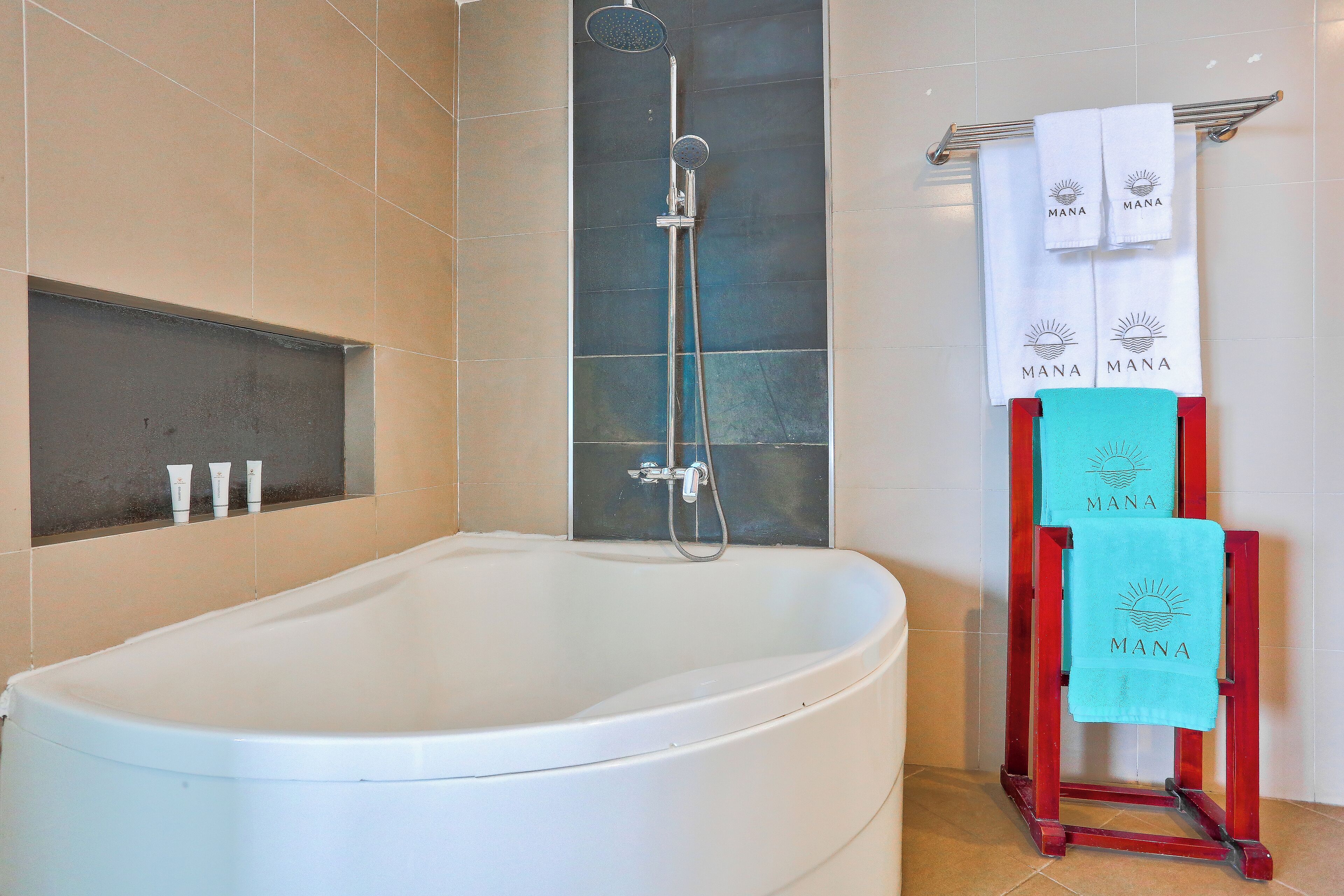 A modern bathroom with a freestanding bathtub, a handheld showerhead, and a towel rack with towels.