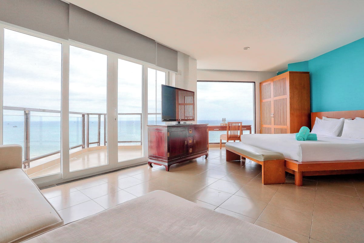 Ein Hotelzimmer mit einem großen Balkon, einem hölzernen Bett, einem Fernseher und einem Holzschrank.