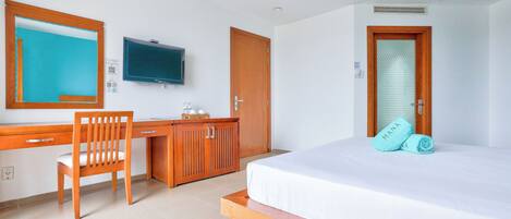 A hotel room with a bed, a desk, a chair, a television, and a wardrobe.