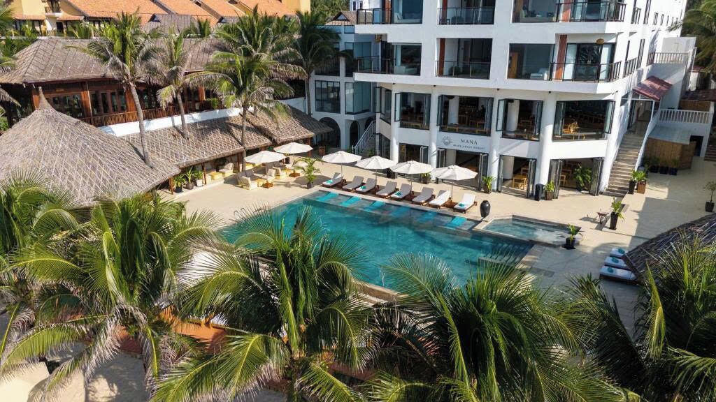 A resort with a swimming pool surrounded by palm trees and lounge chairs.