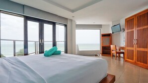 A hotel room with a large bed, a desk, and a TV. There is a view of the ocean through the windows. - Mana Mui Ne Beach Resort & Spa (Mui Ne)