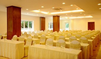 A conference room with rows of tables, each covered with a tablecloth and equipped with chairs.