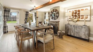 A dining area with a wooden table and chairs, a fireplace, and a modern art piece on the wall. - Great Easton Lodge (Great Easton)