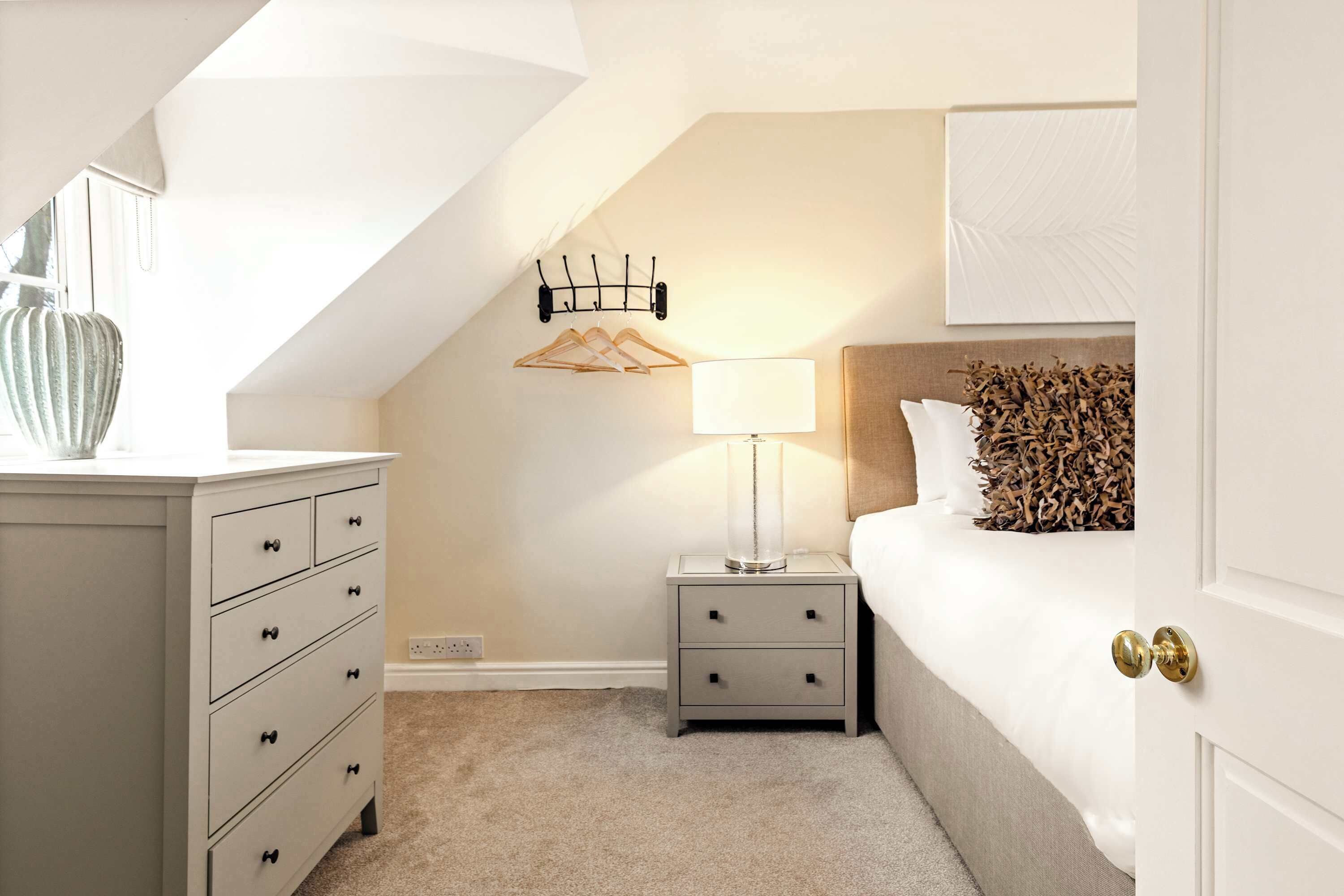 A bedroom with a bed, nightstand, dresser, and a lamp.