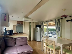 Une petite cuisine équipée avec une cuisinière, un réfrigérateur et un coin repas comprenant une table et des chaises.