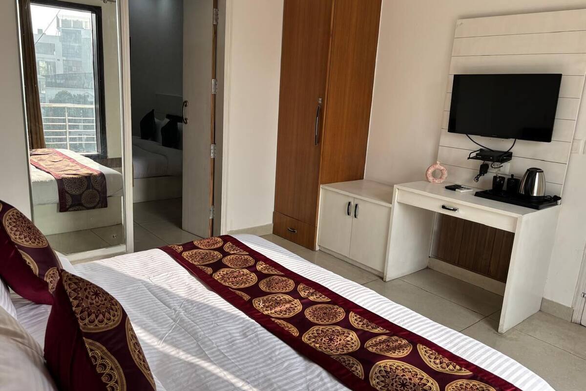 A hotel room with a bed, a desk, a television, and a wardrobe.