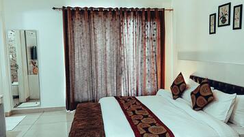 A bedroom with a large bed, a mirror, and a curtain.