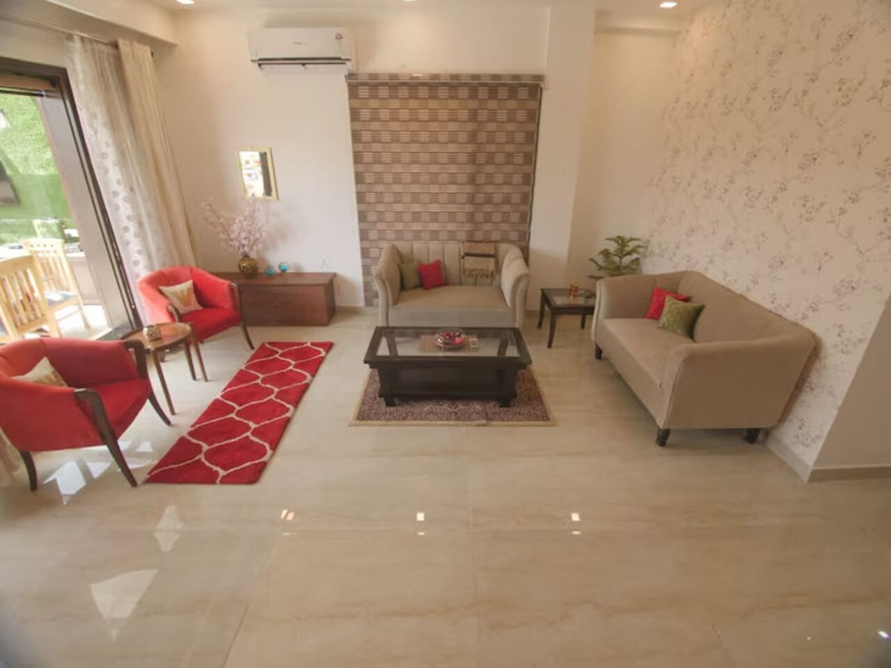 Una sala de estar moderna con una mesa de centro de vidrio, sofás rojo y beige, y un papel tapiz estampado.