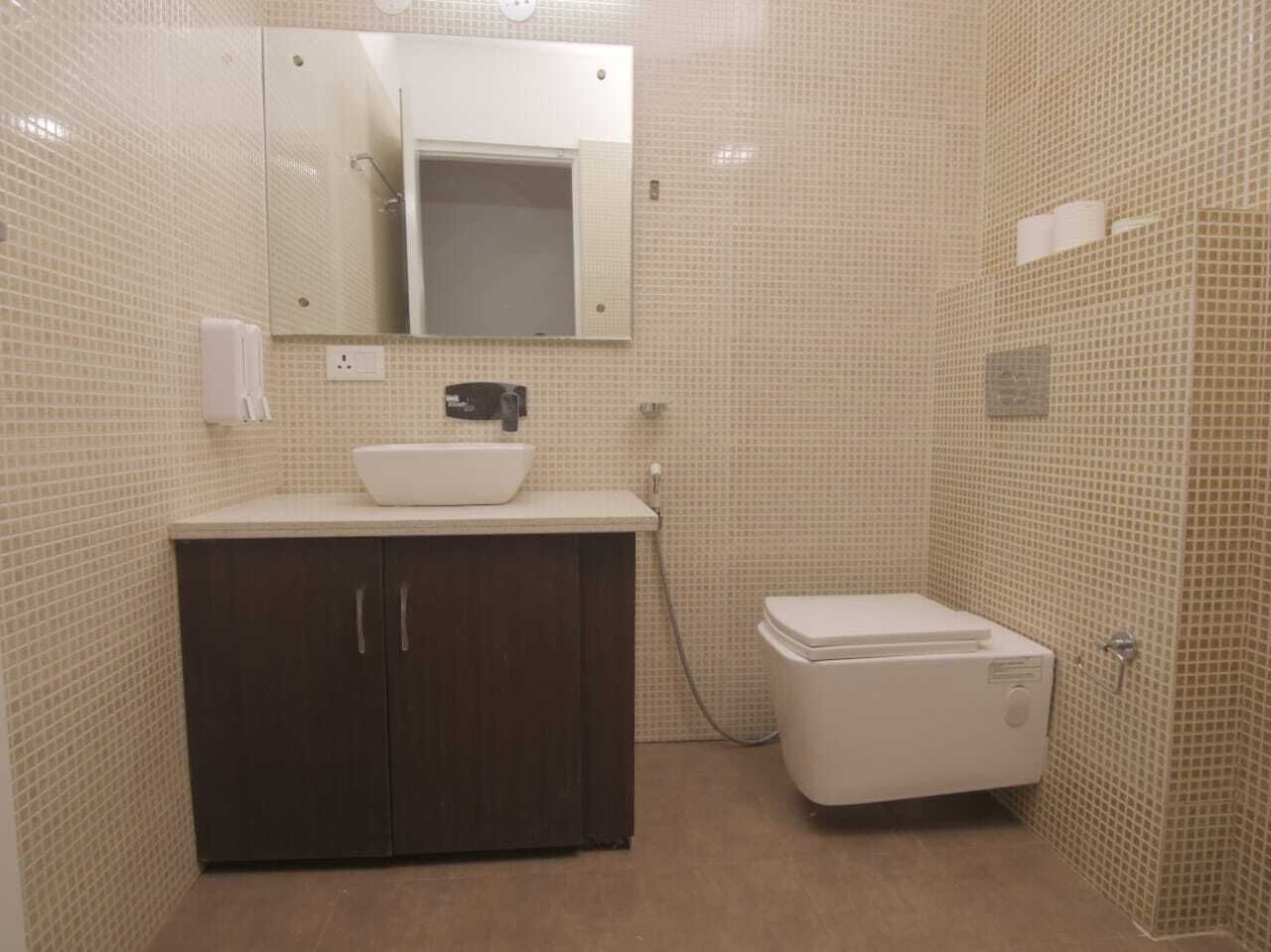 A bathroom with a tiled wall, a sink with a basin, a cabinet, and a toilet.