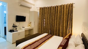 Una habitación de hotel con una cama, televisión, escritorio y ventilador de techo.